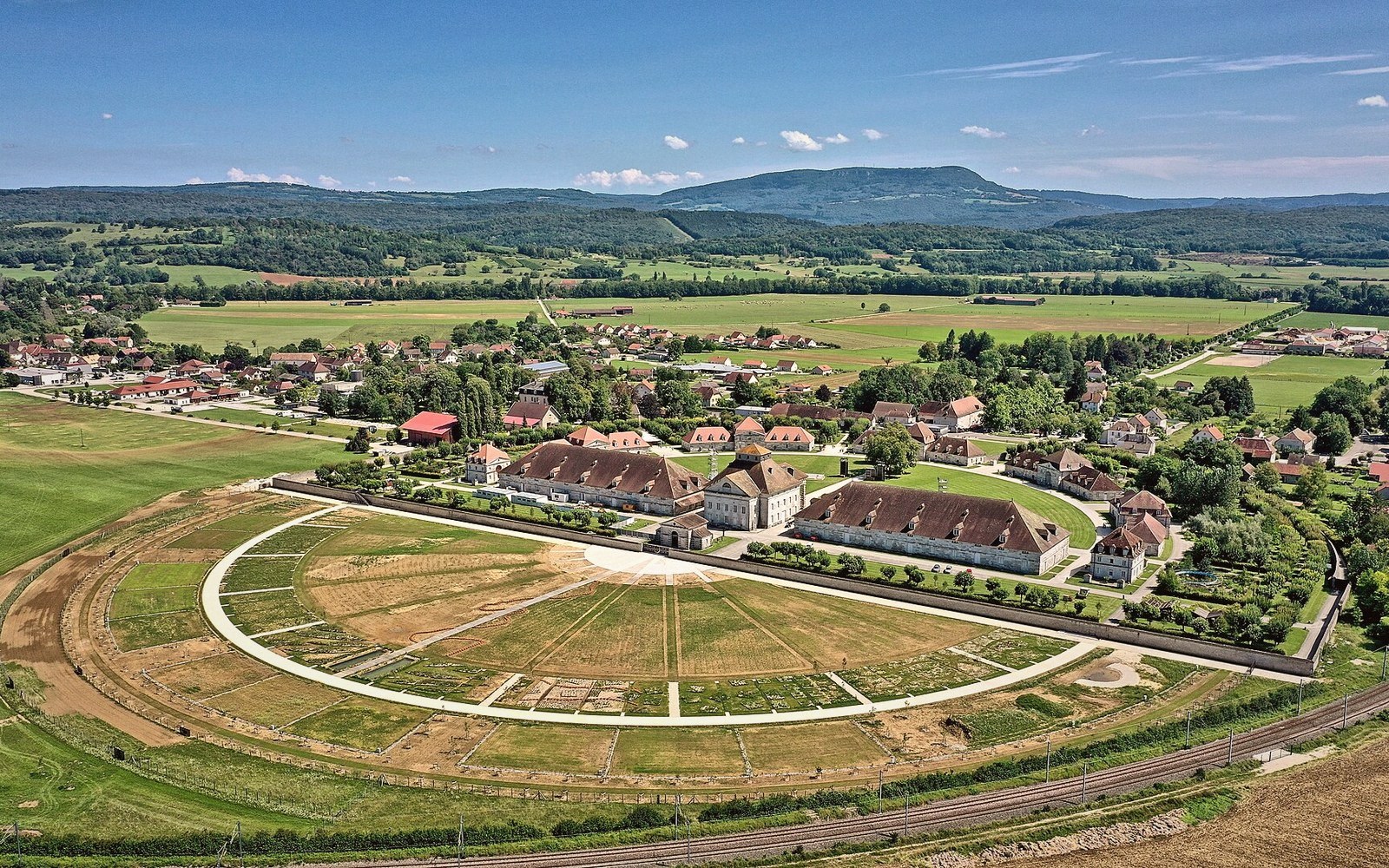 Aerial view of the Royal Saltworks' semicircular buildings surrounded by fields and rolling hills